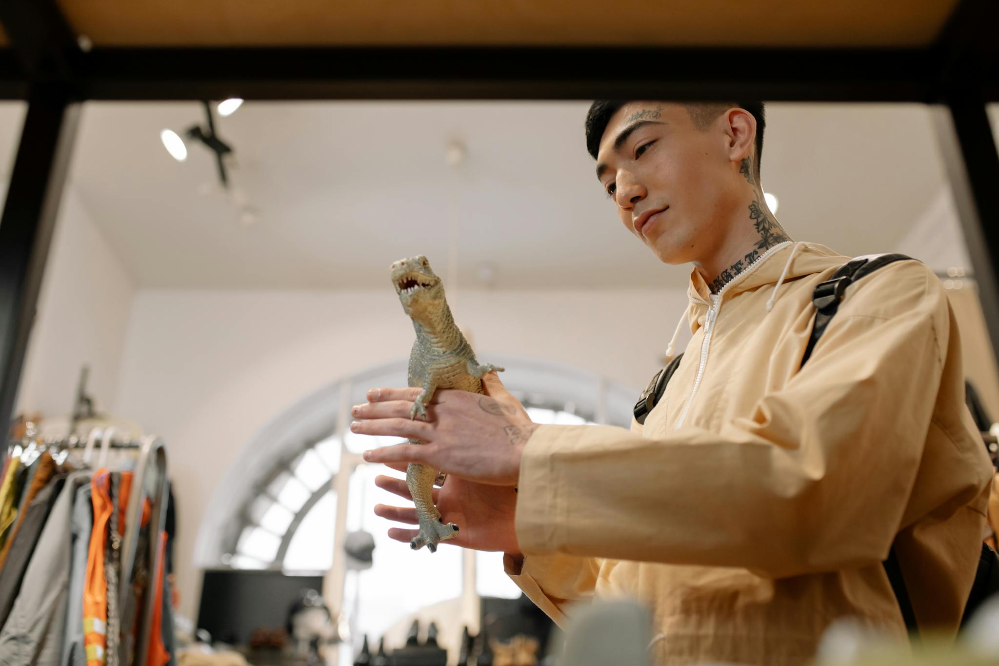 A young man examines a toy iguana inside a trendy fashion and retail store.