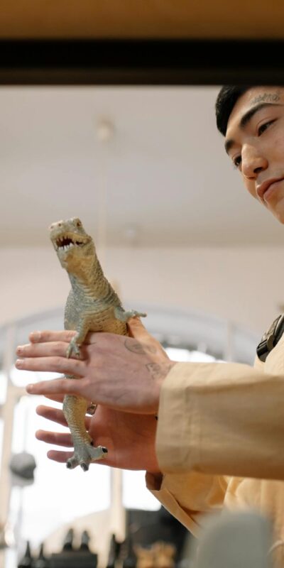 A young man examines a toy iguana inside a trendy fashion and retail store.